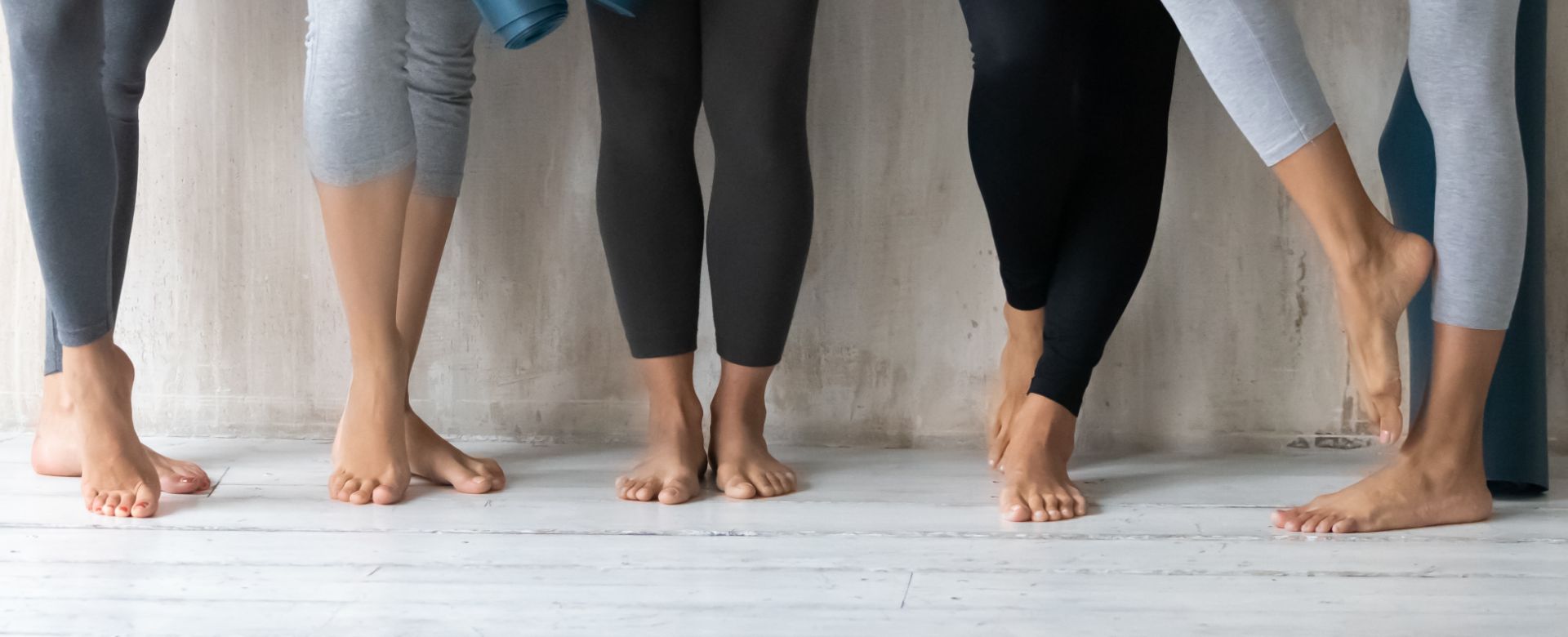 Lower shot of several pairs of bare feet in yoga clothes