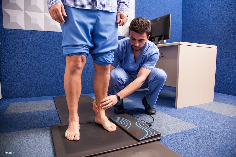A podiatrist examines a man's legs and feet.